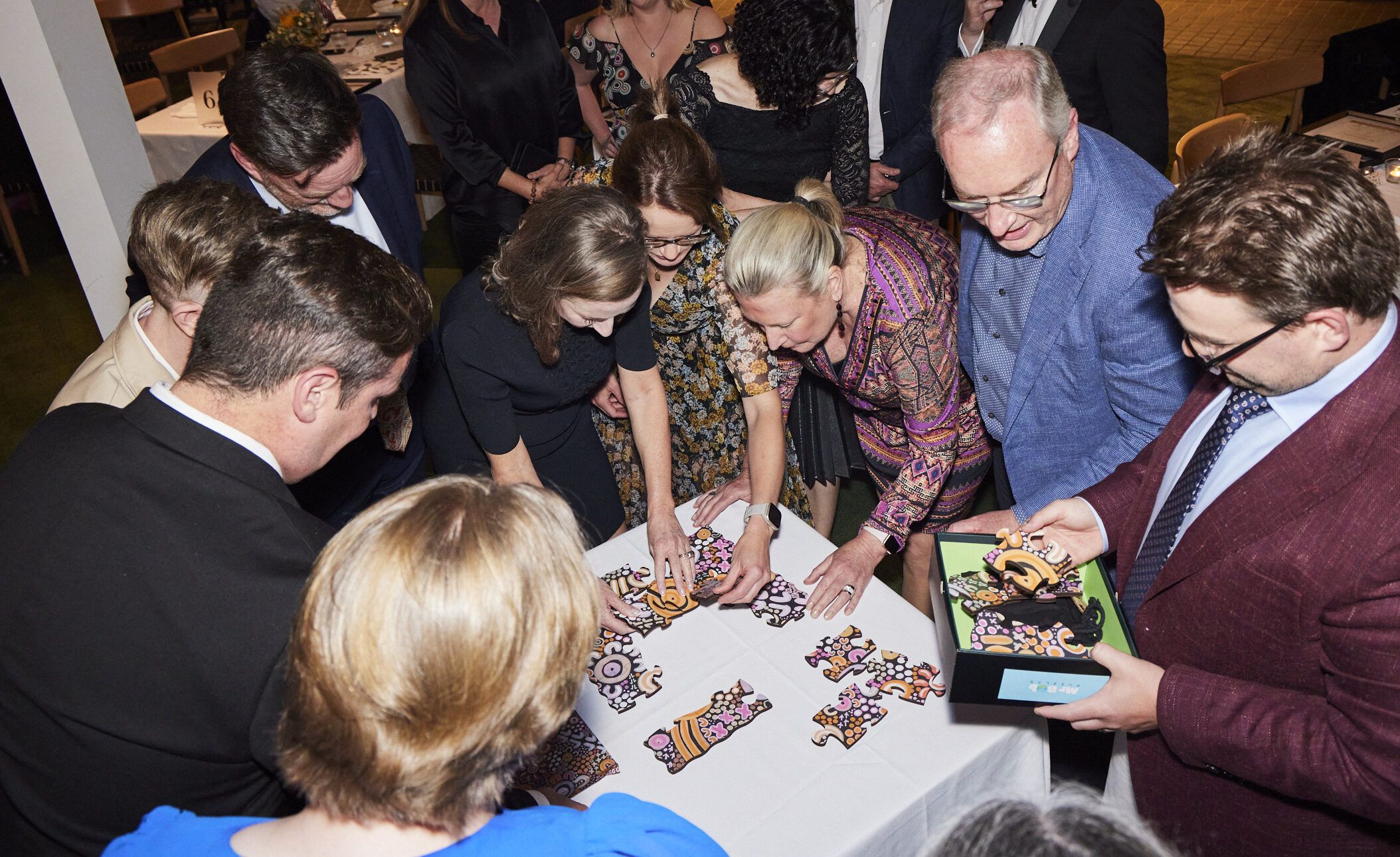 People crowded around a puzzle making it together