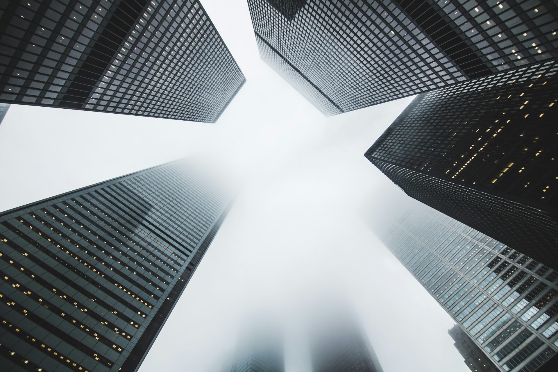 Tall city skyscrapers disappear into foggy sky.